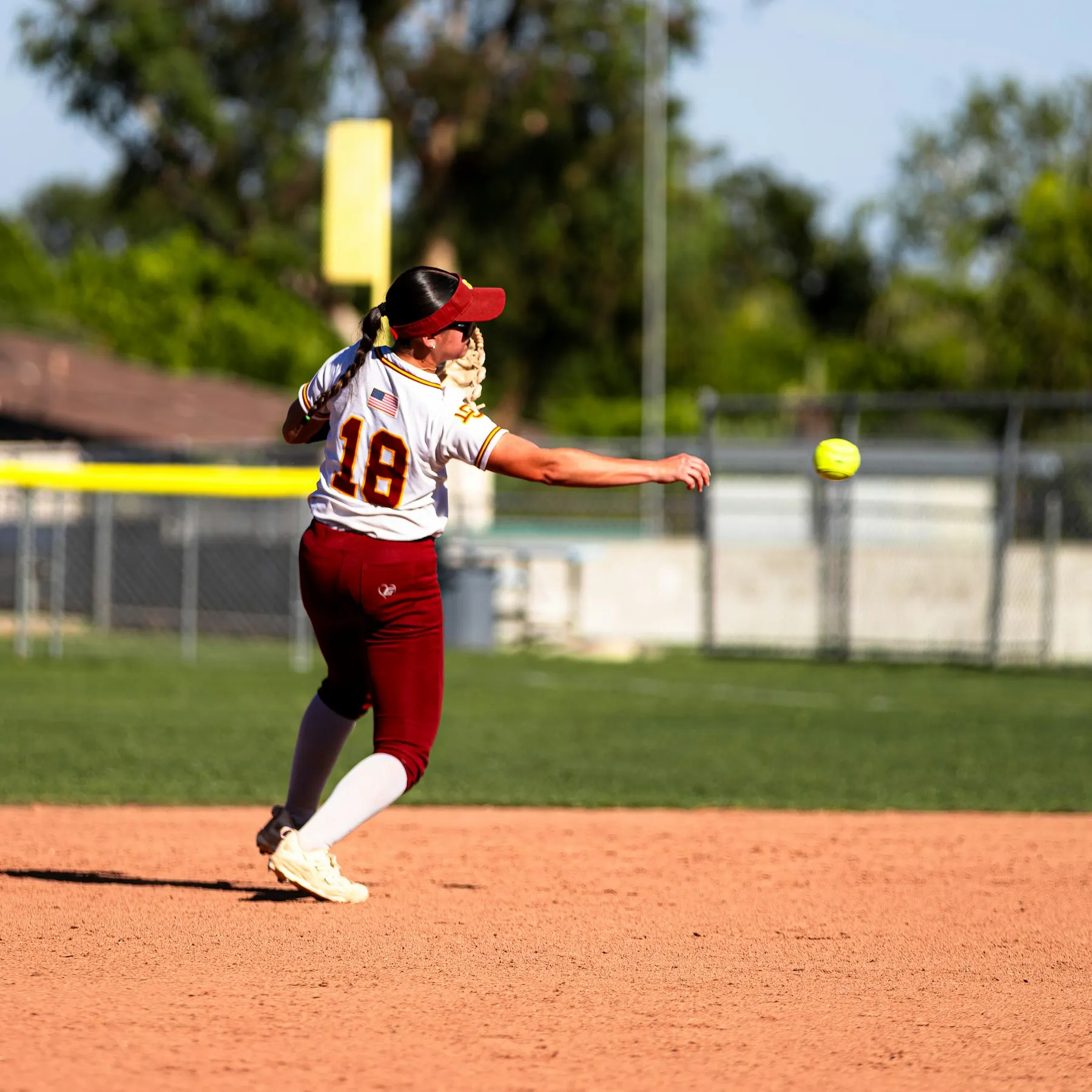 High school softball player throwing during a game